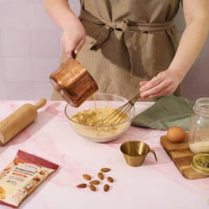 Une femme verse le beurre dans la préparation pour frangipane La Patelière