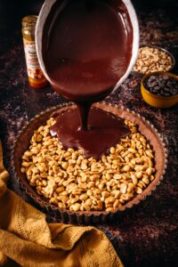 image de chocolat versé sur la tarte chocolat caramel cacahuètes La Patelière